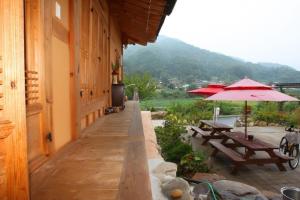 a patio with tables and umbrellas next to a building at Danyang Gahyeonjeong Pension in Danyang