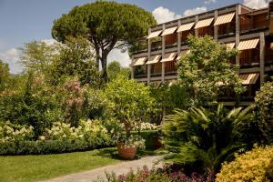 a garden in front of a building with trees and flowers at Hermitage Hotel & Resort Forte dei Marmi - Starhotels Collezione in Forte dei Marmi