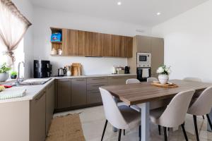 a kitchen with a wooden table and chairs at Bayleaf Coastal Apartment in Marsaxlokk