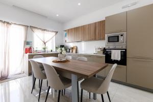 a kitchen with a wooden table and chairs at Bayleaf Coastal Apartment in Marsaxlokk