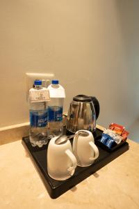 a tray with cups and bottles of water and a tea kettle at Tirupati Resorts in Kota