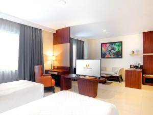 a hotel room with a bed and a computer on a desk at Noormans Hotel Semarang in Semarang