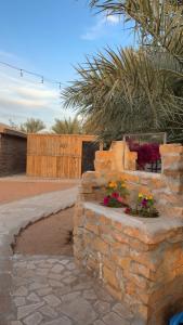 a stone wall with flowers on top of it at منتجع النادر الريفي in Az Zulfi