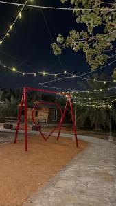a red swing set in a park at night at منتجع النادر الريفي in Az Zulfi