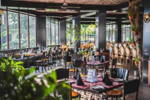 ein Restaurant mit Tischen, Stühlen und Fenstern in der Unterkunft Thilanka Hotel in Kandy