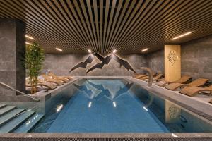 a pool in a hotel with chairs and a swimming pool at Black Mountain Residence & SPA, Odkryj-Białkę in Białka Tatrzańska