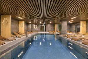 a large swimming pool with chairs in a building at Black Mountain Residence & SPA, Odkryj-Białkę in Białka Tatrzańska