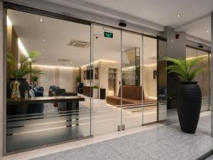 a lobby with glass walls and a vase with plants at Anisa Residence in Salalah