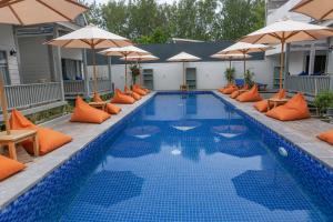 a swimming pool with orange pillows and umbrellas at Hu'u Beach Front Hotel in Gili Trawangan +4 photos
