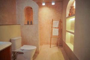 a bathroom with a toilet and a towel rack at Hu'u Beach Front Hotel in Gili Trawangan