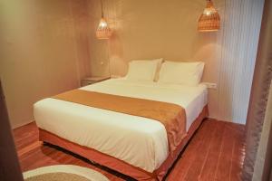 a bedroom with a bed with white sheets and pillows at Hu'u Beach Front Hotel in Gili Trawangan