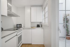 a white kitchen with white cabinets and a microwave at Martin De Aldehuela Apartment in Ronda