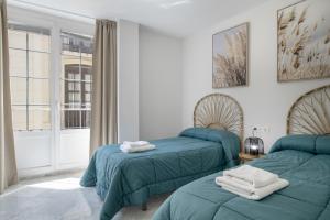 two beds in a room with a window at Martin De Aldehuela Apartment in Ronda
