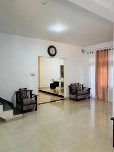 a living room with chairs and a clock on the wall at Boom Town Villa - Anuradhapura in Anuradhapura