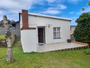 a small white house with a porch at Chill-Ax Cottages in Port Shepstone
