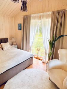a bedroom with a bed and a window and a chair at Escape to Nature - Piparmētras in Mērsrags