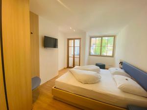 a bedroom with two beds and a flat screen tv at Hotel Lengsteinerhof in Longostagno