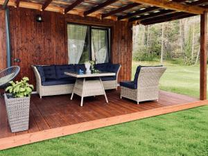 a wooden deck with wicker chairs and a table at Escape to Nature - Piparmētras in Mērsrags +8 photos