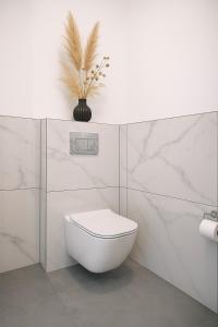 a white bathroom with a toilet and a plant at Apartament Fabryczna TK in Namysłów +13 photos