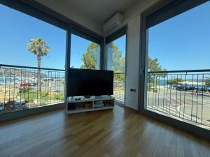 a living room with a flat screen tv and large windows at Koper Sea Apartment in Koper