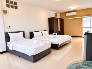 a bedroom with two beds with white sheets at Ruen Aiyara Apartment in Nakhon Ratchasima