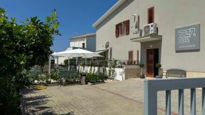 a white building with an umbrella and a patio at Tra 2 Blu Guest House in Belvedere Marittimo