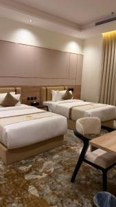 a hotel room with two beds and a table at فندق أروف Aroov Hotel in Taif