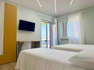 a bedroom with two beds and a desk with a television at Tra 2 Blu Guest House in Belvedere Marittimo