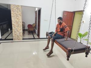 a man sitting on a swing in a room at Hotel Suncity Villa in Trivandrum