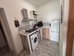 a kitchen with a washing machine and a refrigerator at LA CUEVA DEL LOCO, Bretones 29 in Sanlúcar de Barrameda