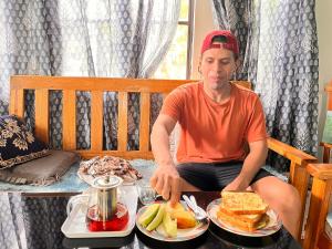 a man sitting on a bench with a tray of food at Live in Nature in Darjeeling