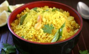 a red bowl of yellow rice with peanuts andilantro at Hotel Lakeview Vadodara in Vadodara