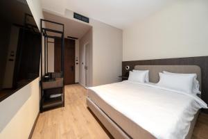 ein Schlafzimmer mit einem großen weißen Bett und einem Spiegel in der Unterkunft Fly Inn Hotel in Vragolija