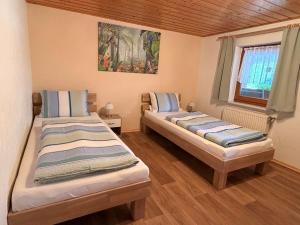 two beds in a small room with a window at Ferienhof Hofmann in Böbrach