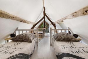 two beds in a attic bedroom with a window at Gîte Ressources - Jacuzzi in La Frenaye