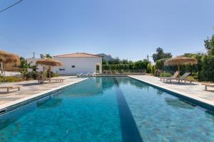 a swimming pool with chairs and umbrellas in front of a house at Vilas Salero in Moncarapacho