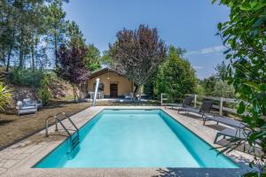a swimming pool with chairs and a house at Glamping - Quinta do Cascalhal in Arco de Baúlhe