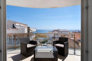 a balcony with chairs and a table and a view of the ocean at Casa Marea in Marzamemi