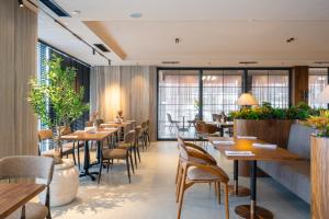 ein Restaurant mit Tischen, Stühlen und Pflanzen in der Unterkunft Fly Inn Hotel in Vragolija
