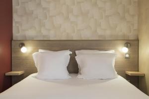 two pillows on a bed with two lights on it at Sure Hotel by Best Western Reims Nord in Reims