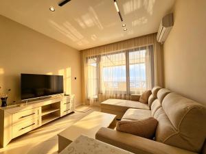 a living room with a couch and a flat screen tv at Europroperties Sirena Apartaments in Golden Sands