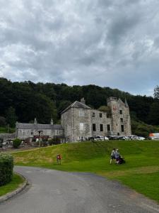 two people sitting on the grass in front of an old building at 87 Loch Murray in Creetown