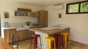 a kitchen with yellow and red stools and a counter at Gite des Egadillias climatisé in Marsanne