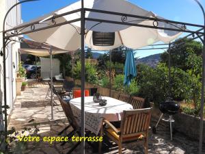 a table and chairs under an umbrella on a patio at Une Heure Bleue in Manosque +22 photos