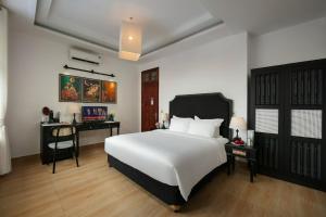 a bedroom with a large white bed and a desk at Maison Bay View Villa Cat Ba in Ðồng Khê Sâu