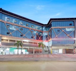 a glass building with palm trees in front of it at Hotel Lakeview Vadodara in Vadodara