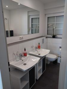 a bathroom with two sinks and a toilet at Lucys Bungalow in Butjadingen +8 photos