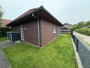a small brick house with a grass yard at Lucys Bungalow in Butjadingen