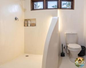 a white bathroom with a toilet and a window at Consul's House Vilanculos in Vilanculos +25 photos