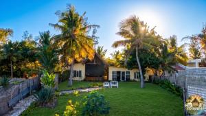 a house with palm trees and a yard at Consul's House Vilanculos in Vilanculos